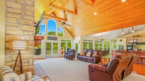 A spacious living area with a stone wall, leather sofas, and a view of the outdoors. - Lakefront Retreat N Norris Lake・Dock W Slide・Games (LaFollette)