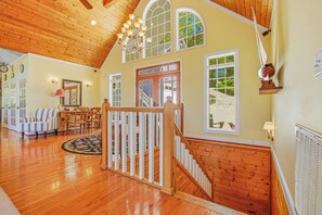 Un intérieur spacieux avec un escalier en bois, un coin repas et de grandes fenêtres.