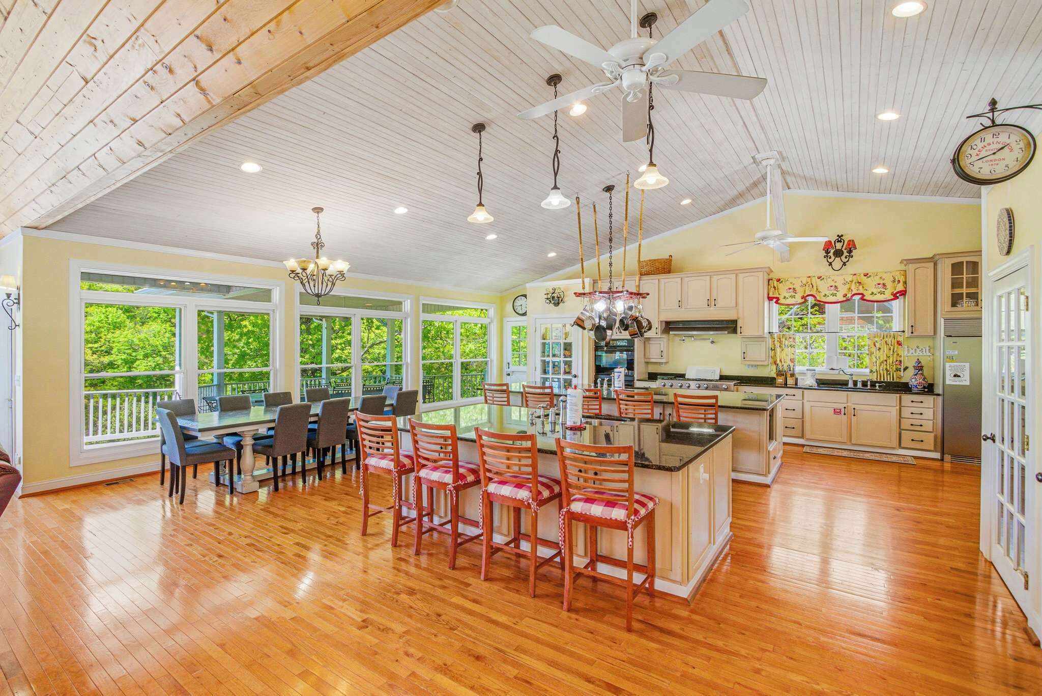 A spacious kitchen with wooden cabinets, a central island, and a dining area with chairs and a table.