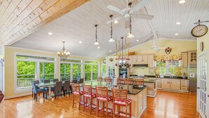 A spacious kitchen with wooden cabinets, a central island, and a dining area with chairs and a table. - Lakefront Retreat N Norris Lake・Dock W Slide・Games (LaFollette)