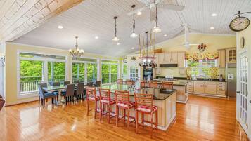 A spacious kitchen with wooden cabinets, a central island, and a dining area with chairs and a table.