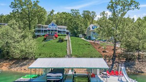 A lakeside property with a dock, a covered boat launch, and a large house with a porch. - Lakefront Retreat N Norris Lake・Dock W Slide・Games (LaFollette)