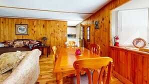 Un intérieur en bois avec une table à manger, des chaises, un canapé et une cuisine en arrière-plan.