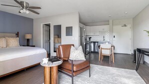 A modern hotel room with a bed, a chair, a small table, and a kitchenette. - Landing | Spectacular Studio, Gym, Yoga Studio (Port Charlotte)