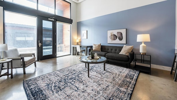 Un salon moderne avec une grande fenêtre, un canapé, une table basse et un tapis.