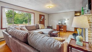 Een ruime woonkamer met een grote hoekbank, een houten salontafel en een lamp.