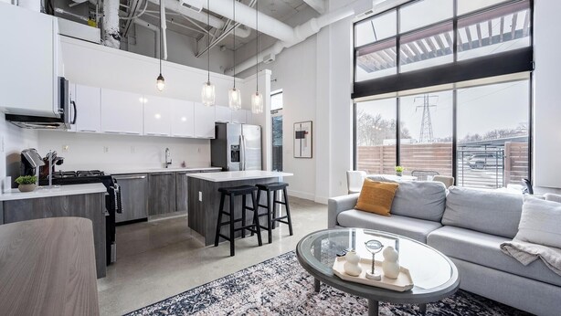A modern kitchen with white cabinets, stainless steel appliances, and a central island with bar stools. - Landing | Beautiful 1BD, Pool, Gym (Royal Oak)