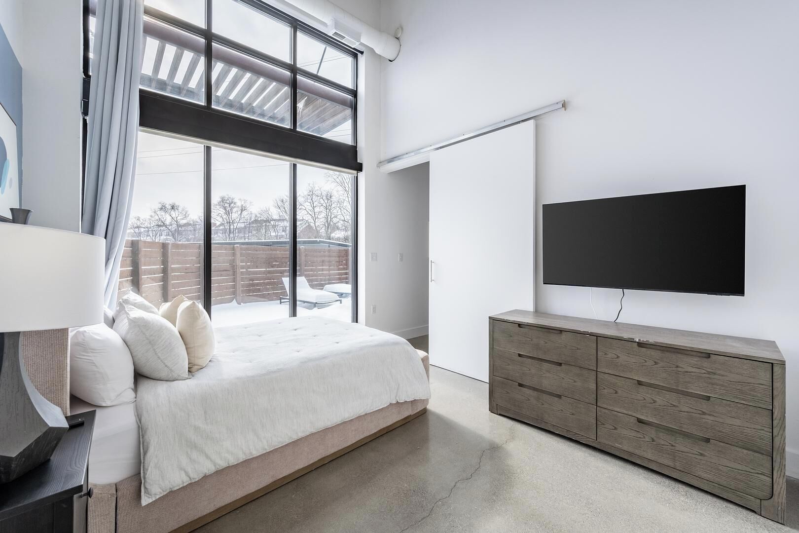 A modern bedroom with a large bed, a TV, and a wooden dresser.