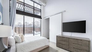 A modern bedroom with a large bed, a TV, and a wooden dresser. - Landing | Beautiful 1BD, Pool, Gym (Royal Oak)