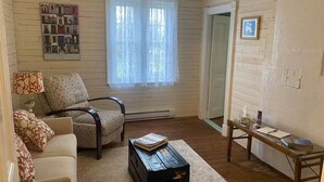 A cozy living room with a patterned armchair, a small wooden coffee table, a lamp, and a framed picture on the wall. - Salt box on Brinson’s (Winterton)