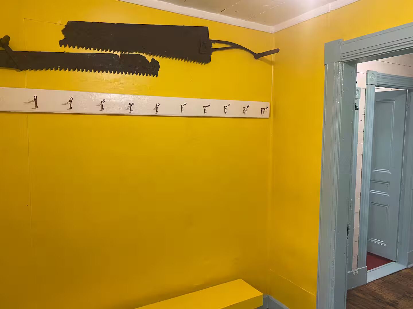 A room with yellow walls, a wooden bench, and a door leading to another room.
