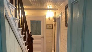 A hallway with a wooden staircase, a white door, and a patterned rug. - Salt box on Brinson’s (Winterton)