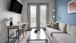Ein modernes Wohnzimmer mit einer Couch, einem Couchtisch, einem Fernseher und einem Schreibtisch.