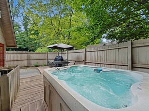 A backyard with a hot tub, wooden deck, patio table, and umbrella. - Near Dollywood Cabin Escape・Deck・Private Hot Tub (Gatlinburg)