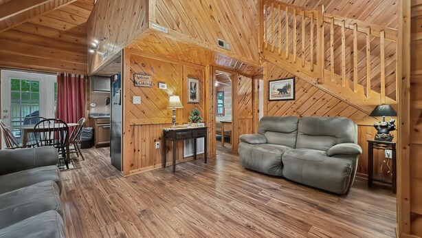 Un intérieur en bois avec un canapé, une table et une lampe, ainsi qu’un escalier.