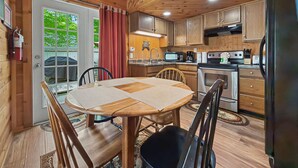 Un intérieur en bois comprenant une table à manger, des chaises, une cuisine équipée et un extincteur.