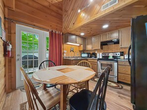 A wooden interior with a dining table, chairs, a kitchen with appliances, and a fire extinguisher. - Near Dollywood Cabin Escape・Deck・Private Hot Tub (Gatlinburg)