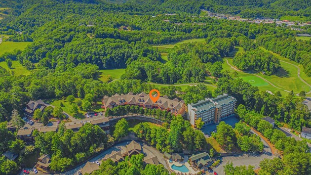 An aerial view of a resort with a swimming pool, golf course, and a large building. - Cozy 2BR Resort Condo Near Dollywood・Pools ・Sauna (Pigeon Forge)