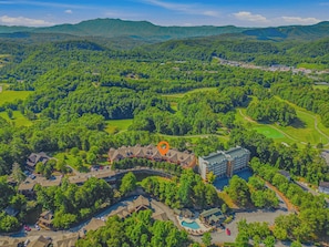 An aerial view of a resort with a swimming pool, golf course, and a large building. - Cozy 2BR Resort Condo Near Dollywood・Pools ・Sauna (Pigeon Forge)