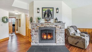 A living room with a stone fireplace, a bear painting, and a sofa. - Cozy 2BR Resort Condo Near Dollywood・Pools ・Sauna (Pigeon Forge)