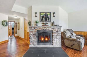A living room with a stone fireplace, a bear painting, and a sofa. - Cozy 2BR Resort Condo Near Dollywood・Pools ・Sauna (Pigeon Forge)