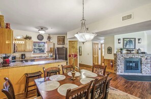 A spacious kitchen with wooden cabinets, a dining area with a large wooden table and chairs, and a stone fireplace. - Cozy 2BR Resort Condo Near Dollywood・Pools ・Sauna (Pigeon Forge)