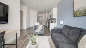 En moderne stue med en grå sofa, et sofabord og et fjernsyn monteret på væggen.