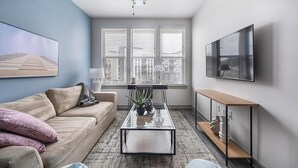 A modern living room with a sofa, coffee table, and TV. - Landing | Stylish 1BD, Pool, Clubhouse (Nashville)