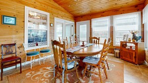 L’intérieur d’une cabane en bois, avec une table à manger, des chaises et un ventilateur de plafond.
