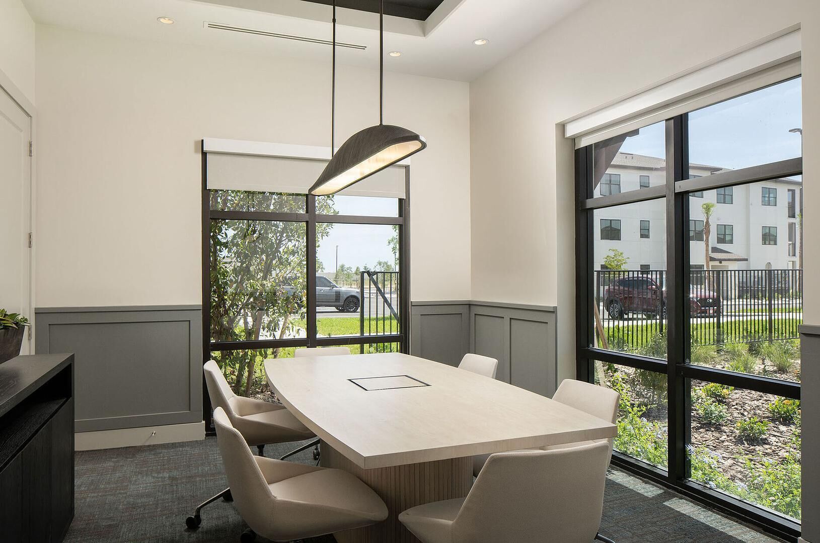 Une salle de conférence équipée d’une grande table, de chaises et d’un luminaire suspendu.