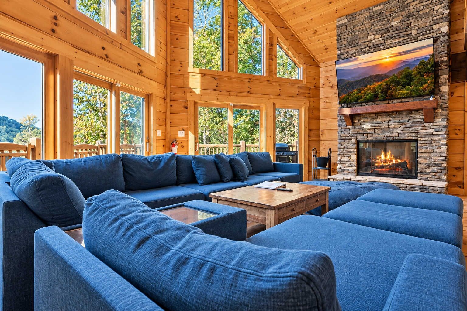 A spacious living room with a large sectional sofa, a fireplace, and large windows offering a view of the outdoors.