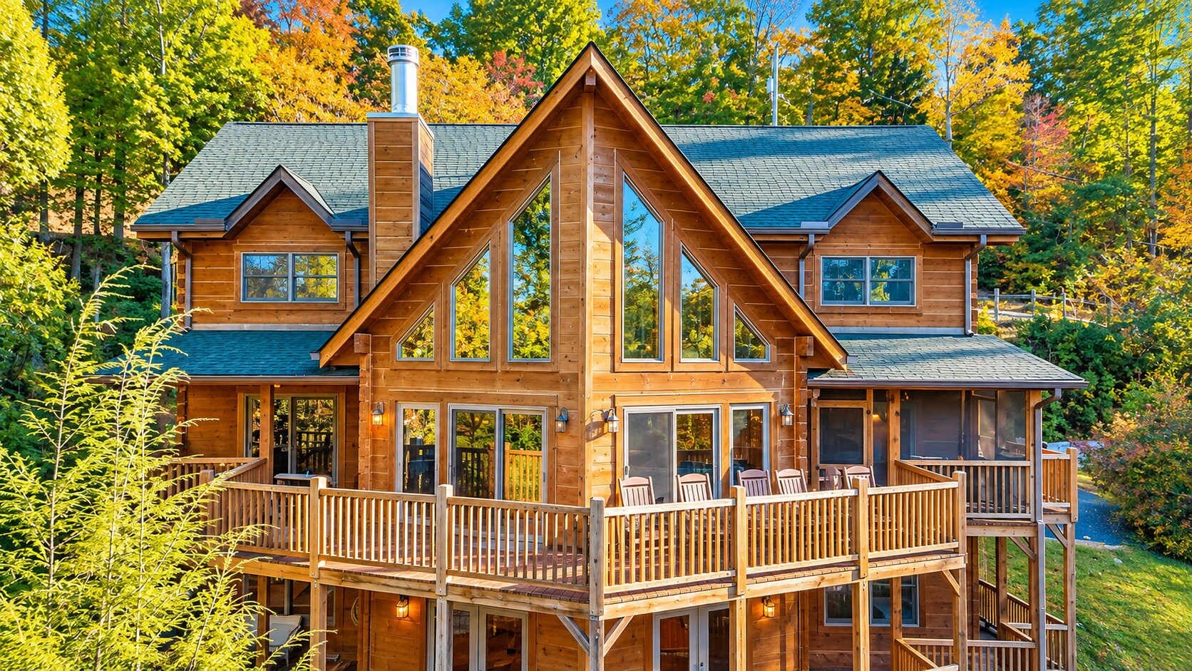 Una cabaña de madera grande con varias terrazas y ventanas amplias, rodeada de árboles.