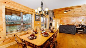 L’intérieur d’un chalet en bois, avec une table à manger dressée pour quatre personnes, entourée de chaises en bois.