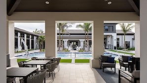 A covered outdoor area with a pool, lounge chairs, and a dining table. - Landing | Stunning 2BD, Pool, Clubhouse (Miromar Lakes)