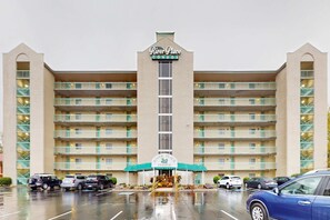 Un hôtel à plusieurs étages, doté d’une entrée principale, de balcons à chaque étage et d’un parking situé à l’avant.