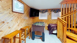 A cozy room with wooden walls, a foosball table, a bed with a purple blanket, and a wooden staircase. - 1 Mi. from Downtown Gatlinburg・Games・River View (Gatlinburg)
