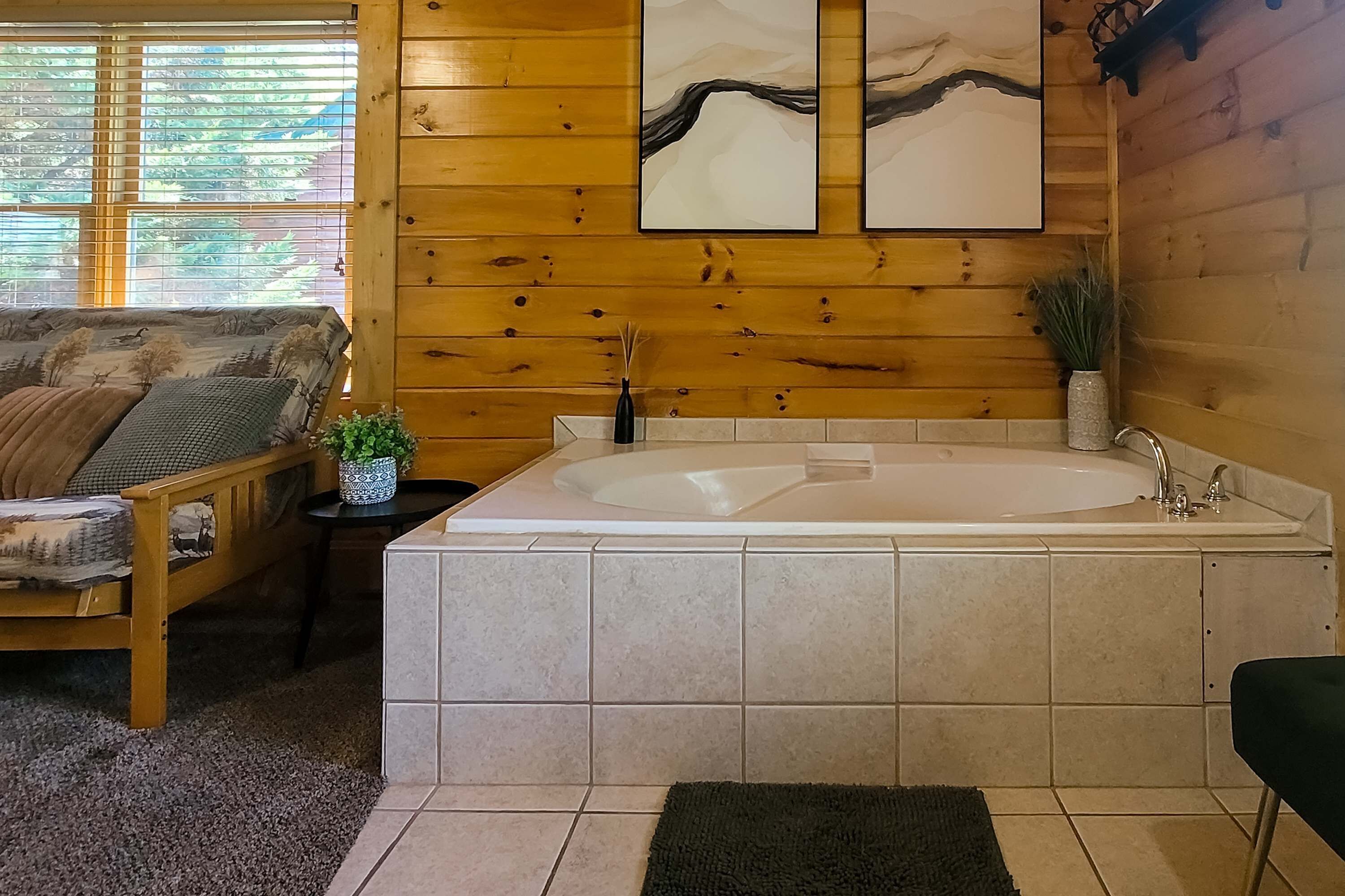 Una habitación con paneles de madera, una bañera grande, un sofá con cojines y una mesita con un florero.
