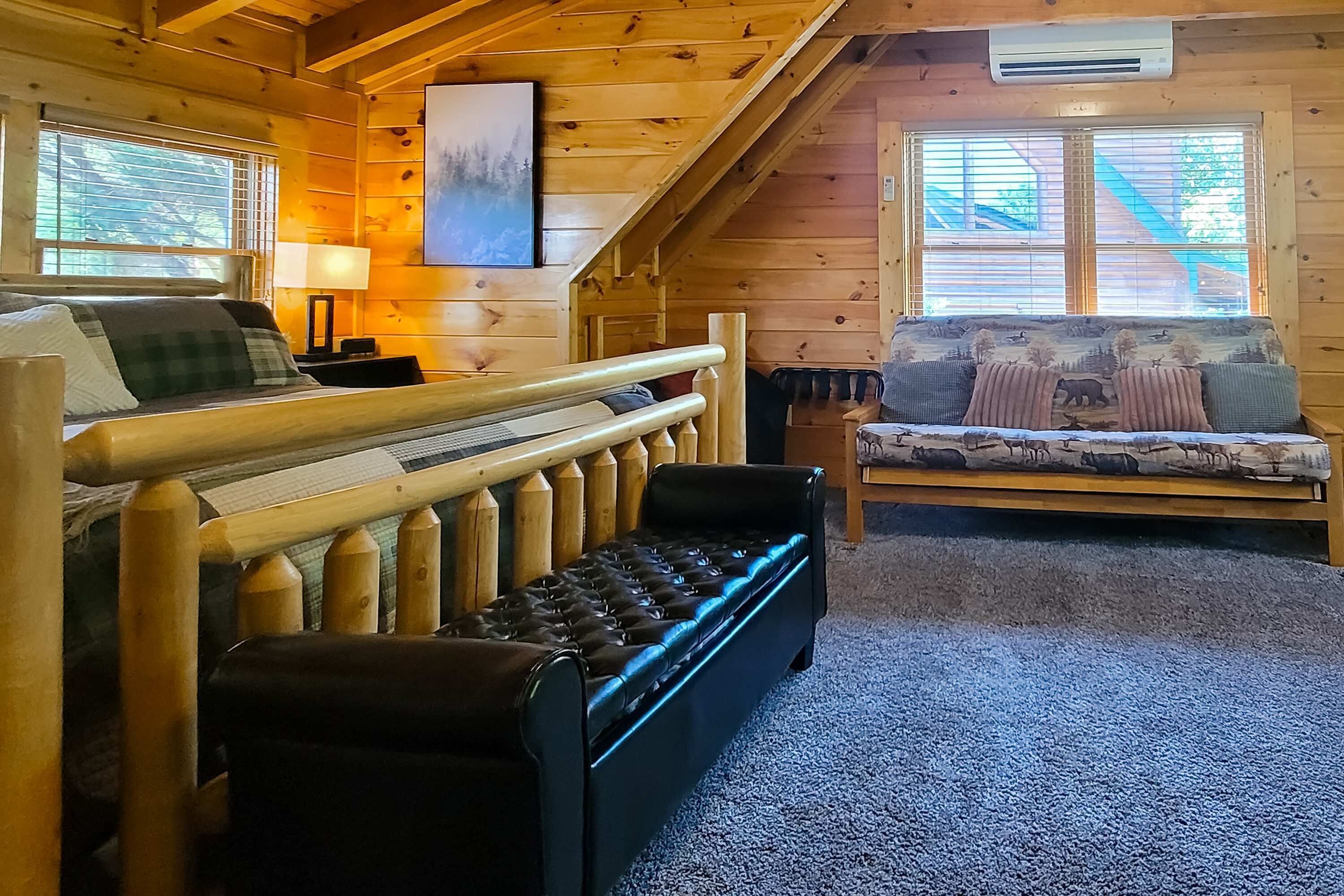 L’intérieur d’un chalet accueillant, avec un lit, un canapé et une rambarde en bois.