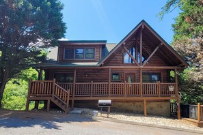 A wooden cabin with a balcony, a mailbox, and a stone wall. - Spacious Cabin, Sleeps 16, Games, Near Downtown (Pigeon Forge)