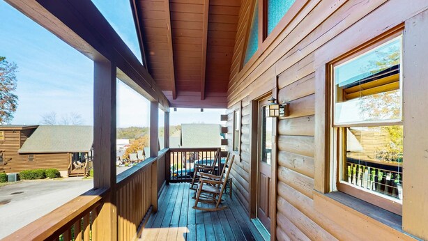 Een houten veranda met schommelstoelen, een houten leuning en uitzicht op de omgeving.