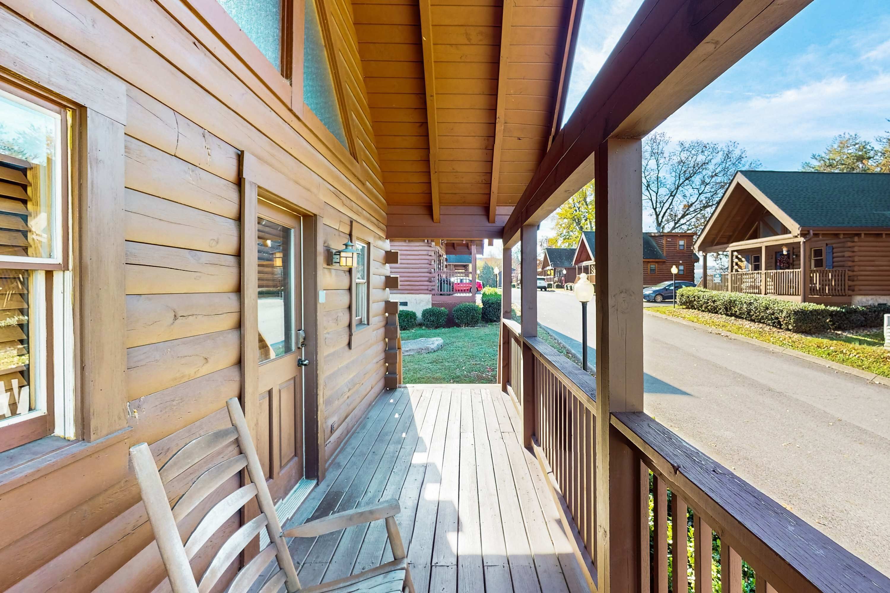 Une cabane en bois avec une véranda, un banc et une vue sur une rue et d’autres cabanes.