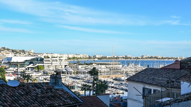 A marina with numerous boats, a clear blue sky, and buildings in the background. - L'Illusioniste studio vue mer dans le Suquet (Cannes)