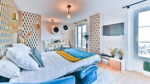 A modern bedroom with a bed, bedside tables, a TV, and a window. - L'Illusioniste studio vue mer dans le Suquet (Cannes)