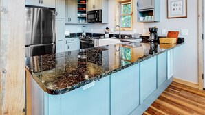 Una cucina moderna con elettrodomestici in acciaio inossidabile, un piano di lavoro in granito e mobili color azzurro chiaro.