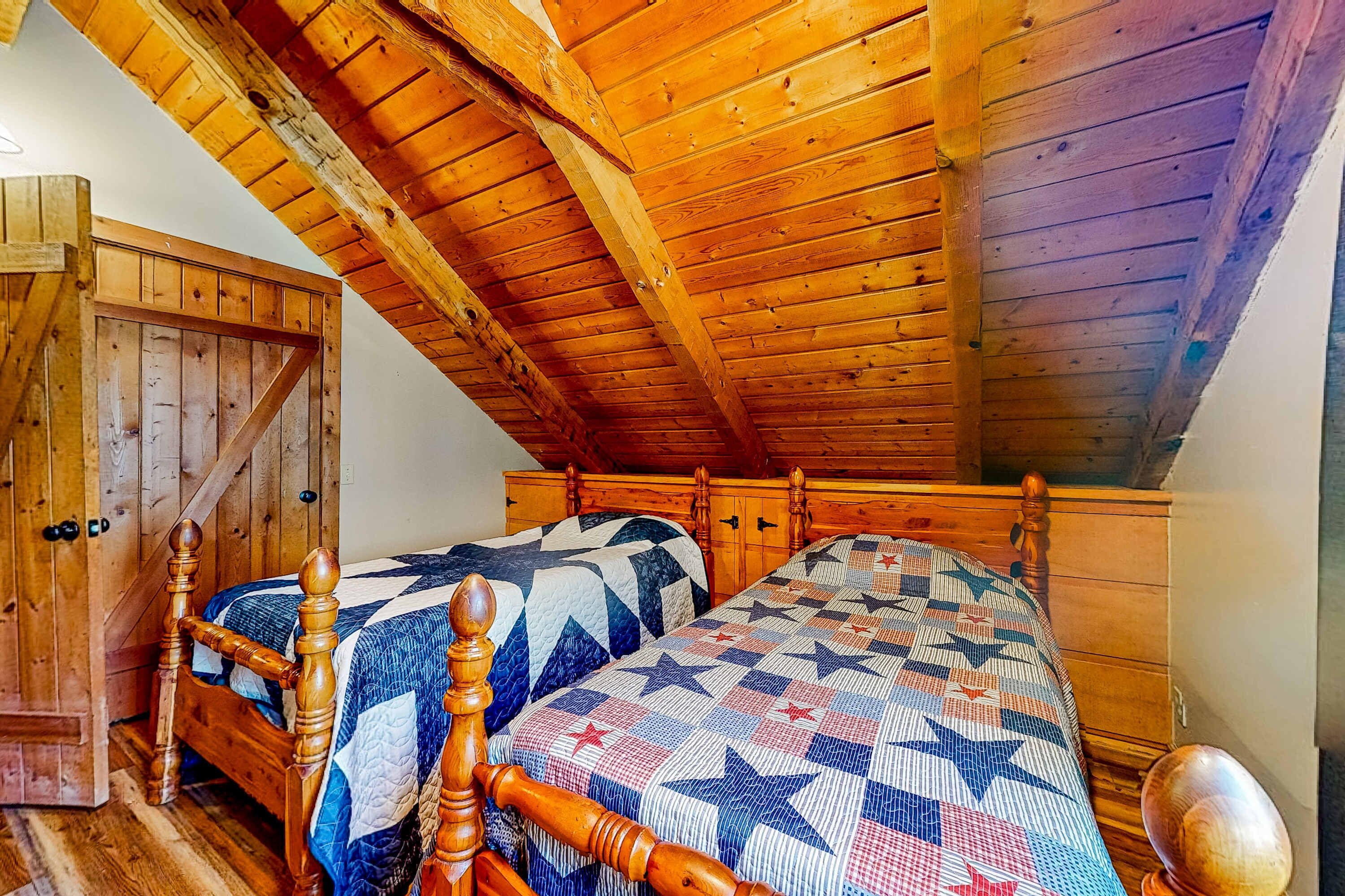 Un dormitorio con dos camas de madera, un armario de madera y un techo inclinado.