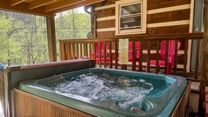 Un jacuzzi en una terraza de madera con vistas a árboles.