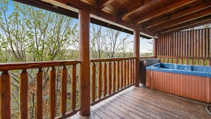 Une terrasse en bois avec un jacuzzi et une vue sur les arbres.