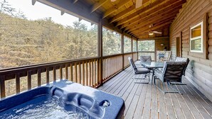 A wooden deck with a hot tub, outdoor furniture, and a view of the forest. - Secluded Retreat, Sleeps 4・Furnished Deck・Hot Tub (Sevierville)