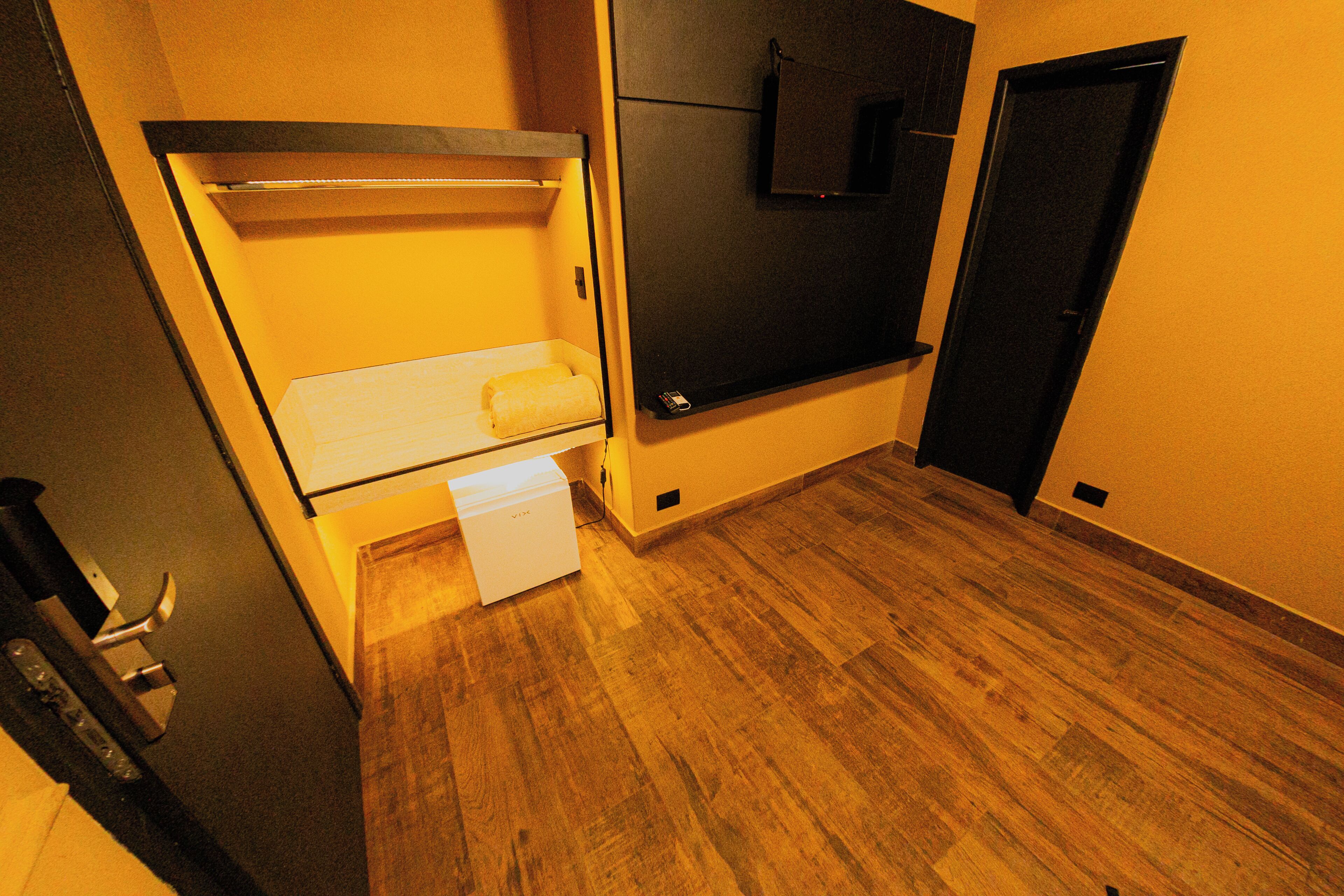 Une petite pièce comprenant un lit superposé, un petit bureau et une porte.