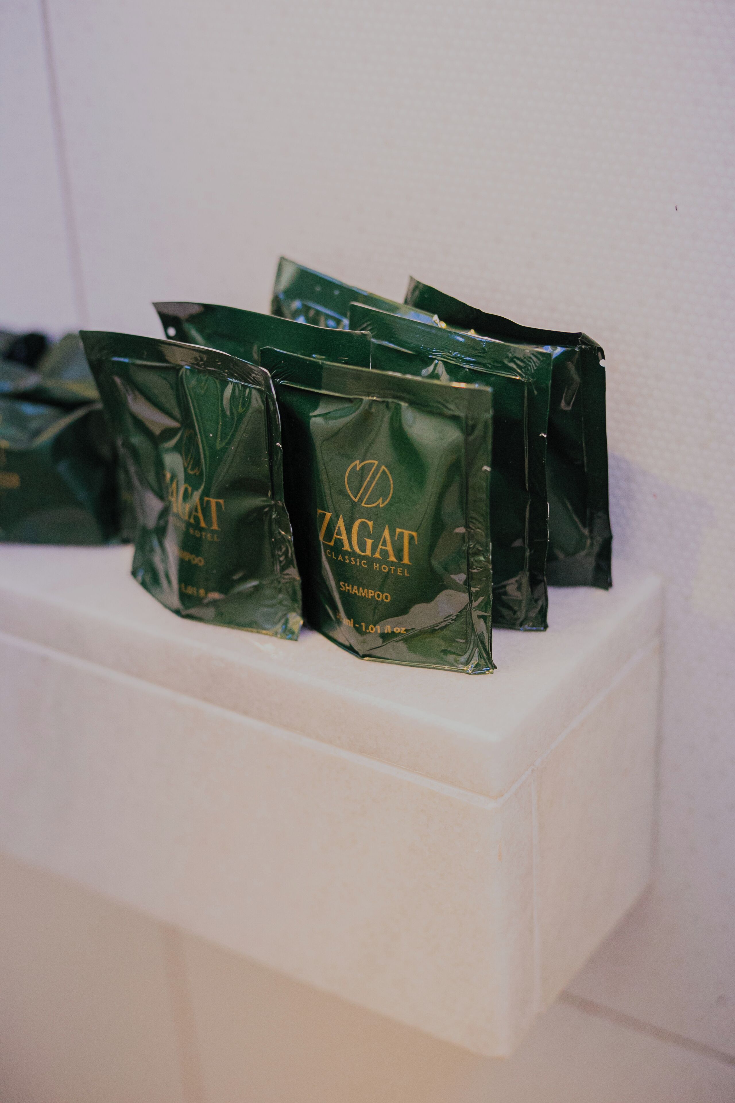 A row of green bags labeled 'ZAGAT' on a white shelf.
